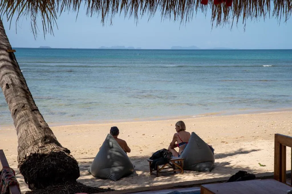 Guests relaxing on beanbags under a palm tree at Isara Lanta beachfront Koh Lanta